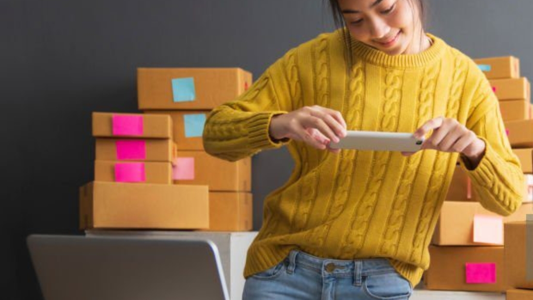 Young women taking photo to shoes with cell telephone or smartphone digital camera for post to sell online on the Internet and preparing pack product box. Selling online ideas concept