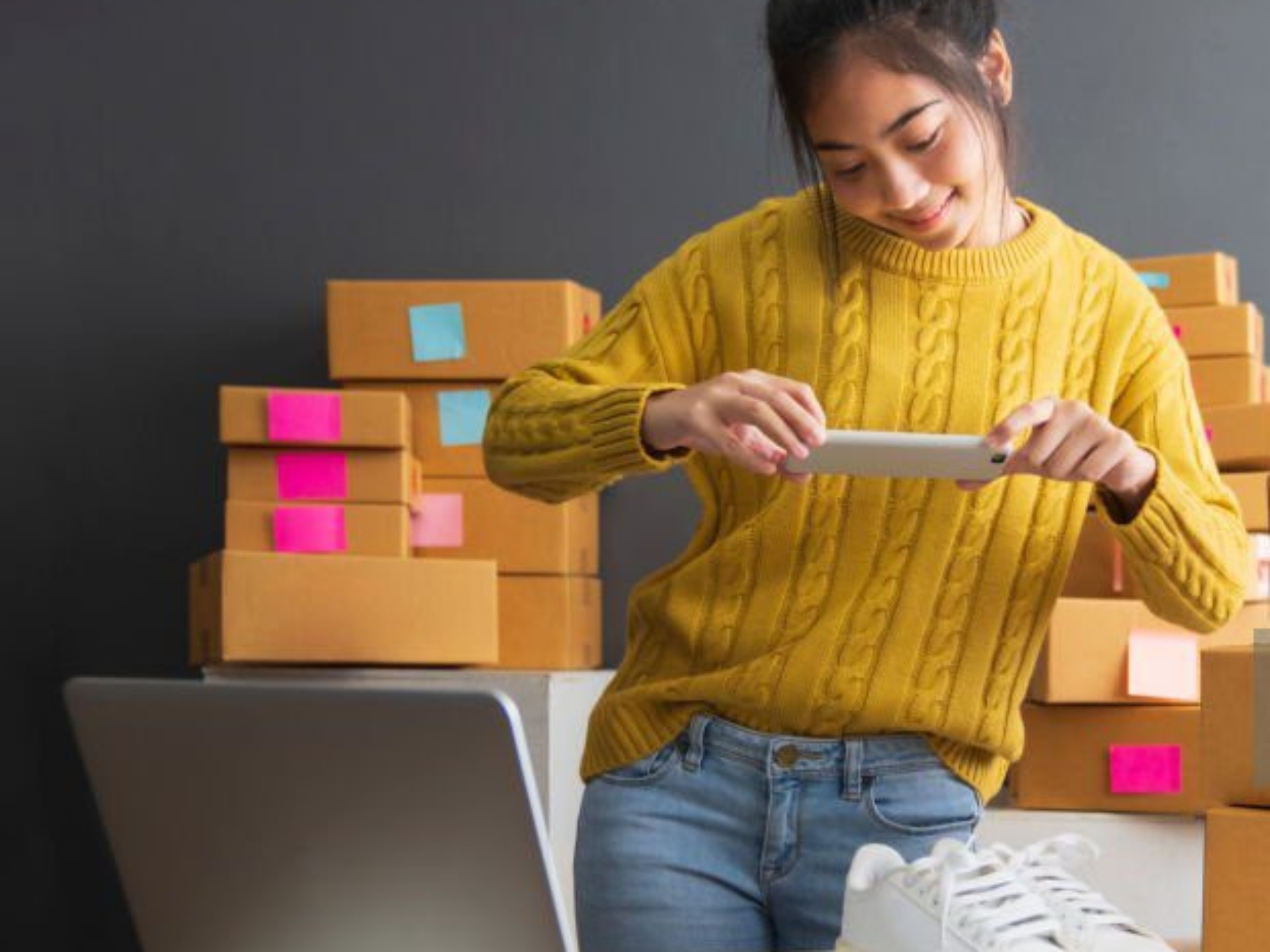 Young women taking photo to shoes with cell telephone or smartphone digital camera for post to sell online on the Internet and preparing pack product box. Selling online ideas concept