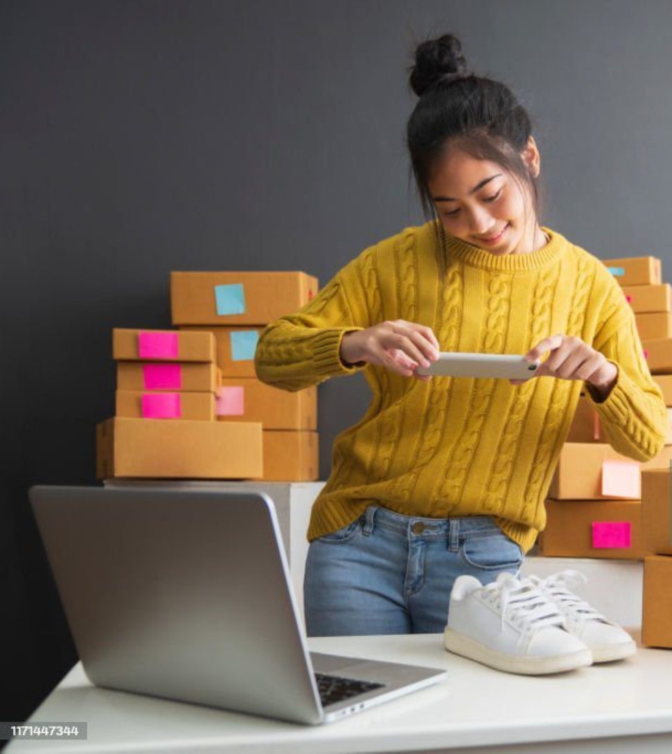 Young women taking photo to shoes with cell telephone or smartphone digital camera for post to sell online on the Internet and preparing pack product box. Selling online ideas concept